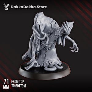 May include: A grey figurine of a robed figure holding a staff-like object. The figure has stitched seams and a tattered appearance. The base is black, and the figure measures 7.1 cm from top to bottom. The DakkaDakka.Store logo is in the upper left corner.