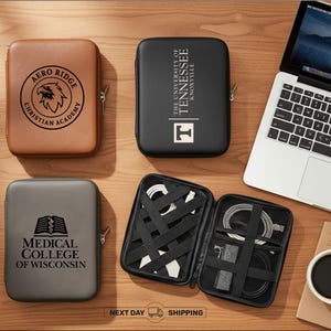 Peut inclure: Vue aérienne de plusieurs étuis techniques zippés marron, noirs et gris, chacun avec un logo. Un étui est ouvert, révélant des câbles organisés. Un ordinateur portable, une tasse de café et un carnet sont également visibles. Sur une surface en bois.