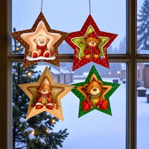 Peut inclure: Quatre décorations de Noël en forme d'étoile suspendues devant une fenêtre. Chaque étoile présente une illustration d'ours en peluche au centre, avec des couleurs rouge, verte et marron. L'arrière-plan montre une scène hivernale enneigée.