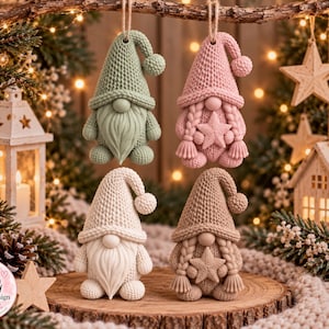 May include: Four gnome ornaments with a textured knit pattern. Two gnomes have long beards and two have braided hair with a star on their chest. The colors are sage green, soft pink, cream, and tan. Each gnome wears a pointed hat with a pom-pom.