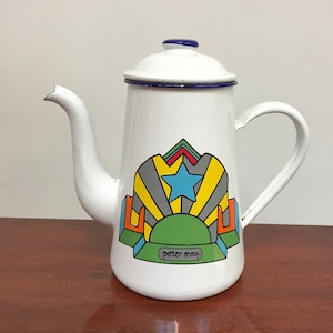 以下が含まれることがあります： 青い縁取りとピーター・マックスのデザインが施された白いエナメル製のコーヒーポット。星、幾何学的な形、そして「peter max」の文字が描かれています。