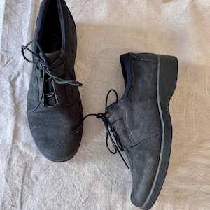 Op de afbeelding: Een paar zwarte veterschoenen. De schoenen hebben een ronde neus en een lage hak. De veters zijn zwart en vastgebonden. De schoenen zijn gemaakt van een su&egrave;de-achtig materiaal.