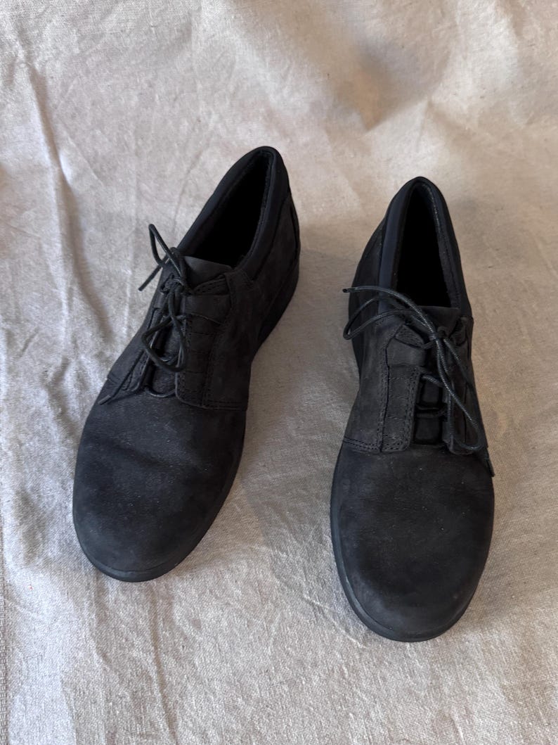 Op de afbeelding: Een paar zwarte veterschoenen. De schoenen hebben een ronde neus en een lage hak. De bovenkant lijkt van su&egrave;de of een vergelijkbaar materiaal te zijn. De veters zijn zwart en vastgeknoopt.
