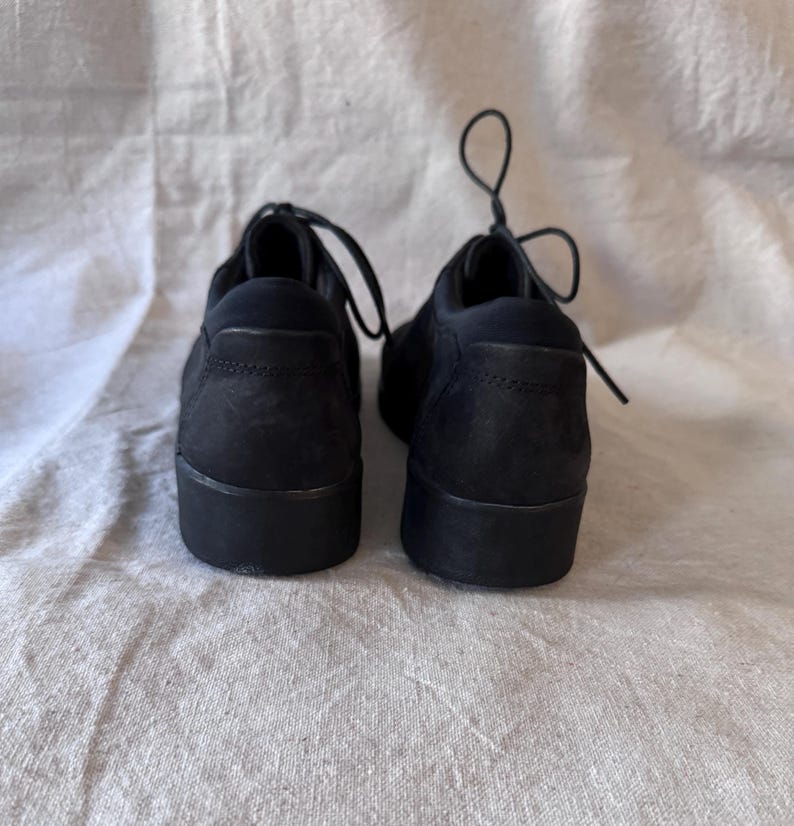 Op de afbeelding: Een paar zwarte veterschoenen met een bovenwerk met textuur en een dikke zool. De schoenen zijn gemaakt van een mat materiaal en worden gepresenteerd tegen een neutrale achtergrond.