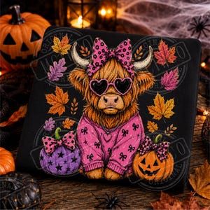 Può includere: Una felpa nera con la grafica di una mucca Highland marrone che indossa un maglione rosa con motivo a fiocchi, un fiocco rosa sulla testa e occhiali da sole a forma di cuore. La mucca è affiancata da una zucca viola e una zucca arancione.