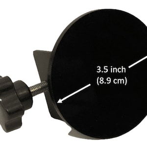 May include: A black circular clamp featuring a threaded metal screw and a black plastic knob. The circular face has a diameter of 3.5 inches as indicated by the white arrow graphic and text printed directly on the surface of the object.