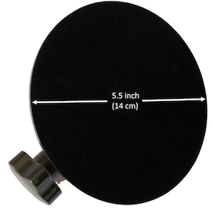 May include: A circular black suction cup with a dark brown knob attached to the side. A white arrow spans the diameter of the suction cup, indicating a measurement of 5.5 inches. The object is presented against a plain white background.