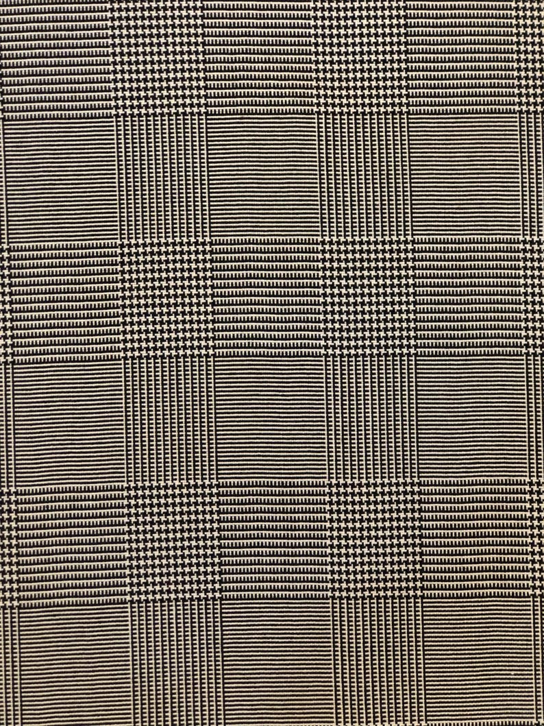 Pu&ograve; includere: Primo piano di un tessuto bianco e nero con motivo a pied-de-poule e righe. Il design presenta una disposizione a griglia di quadrati alternati a pied-de-poule e righe, creando un effetto visivo strutturato. Adatto per abbigliamento o arredamento.