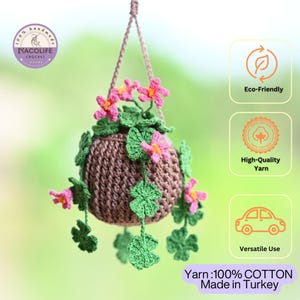 May include: A handmade crochet hanging planter with pink flowers and green leaves. The planter is brown and has a woven texture. The image includes text that says "Eco-Friendly", "High-Quality Yarn", and "Versatile Use". The yarn is 100% cotton and made in Turkey.