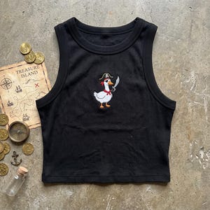 May include: A black ribbed tank top featuring an embroidered graphic of a white goose wearing a pirate hat with a skull and crossbones, an eye patch, and a red neckerchief while holding a silver sword in its wing, centered on the chest.