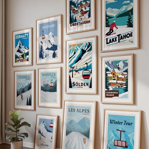 May include: A collection of framed travel posters featuring ski resorts and mountain landscapes. The posters include destinations like Zermatt, Switzerland, Lake Tahoe, and Les Alpes. The posters are in wooden frames and displayed on a wall and floor.