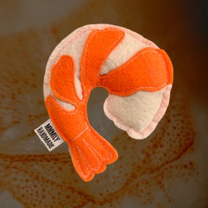 May include: A handmade felt shrimp toy in orange and white with the text "MAMMILY HANDMADE" on the tag.