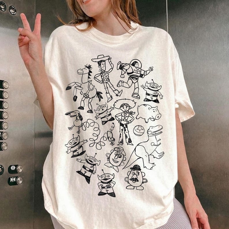 Camiseta unisex de Disney Pixar Toy Story Doodles Comfort Colors, camiseta de dibujos animados de Woody y Buzz Lightyear, camiseta a juego para regalar en un viaje familiar a Disneyland. Natural/ Ivory