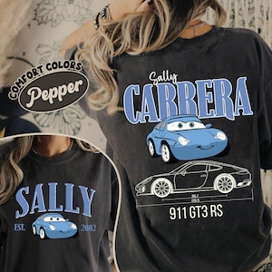 May include: Dark gray Comfort Colors t-shirt featuring the text "Sally Carrera" in blue, along with a cartoon image of a blue car. The shirt also includes a graphic of a car with dimensions and the text "911 GT3 RS".