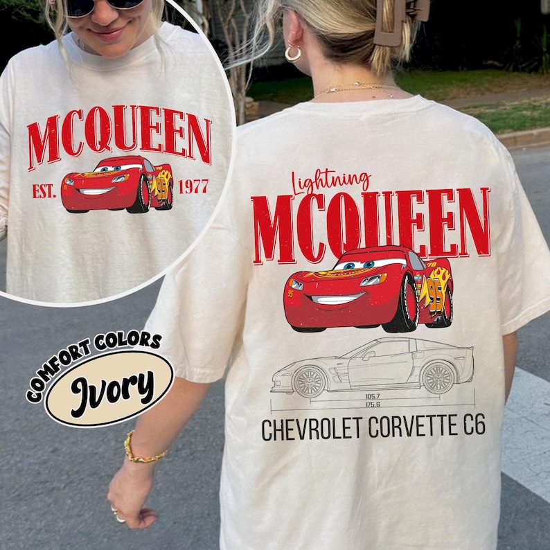 May include: Ivory-colored t-shirt featuring the text "MCQUEEN" and a red cartoon car graphic. The shirt also displays "EST. 1977" and "Lightning MCQUEEN" with a Chevrolet Corvette C6 schematic.