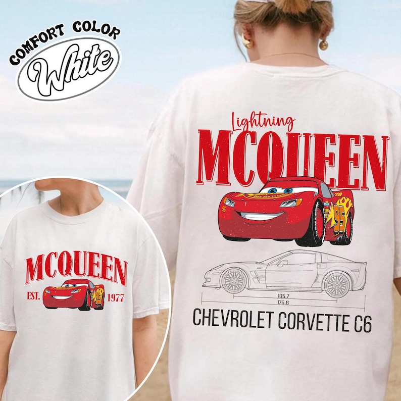 May include: White t-shirt featuring Lightning McQueen from the Cars movie. The design includes the text "Lightning McQueen" in red, a cartoon image of the car, and a schematic of a Chevrolet Corvette C6. The shirt also has the text "Comfort Color White".