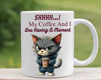 May include: White ceramic mug featuring a cartoon cat holding a coffee cup. The mug has the text "SHHHH... My Coffee And I Are Having A Moment" printed on it.