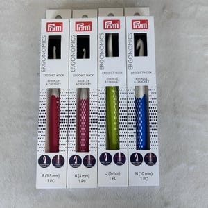 May include: Four crochet hooks in their original packaging. Each package features a different colored handle: red, magenta, green, and blue. The packaging includes the hook size in millimeters and inches, and the brand name "Prym".