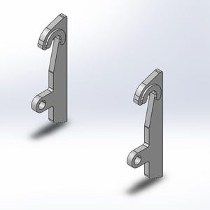 Può includere: Due ganci in metallo argentato con la parte superiore curva e un piccolo foro nella parte inferiore. I ganci sono progettati per essere fissati a una superficie.