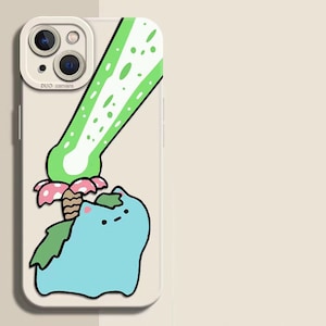 May include: A phone case featuring a cartoon illustration of a blue creature with green leaves and a green and white design. The case has a white border and a camera cutout.