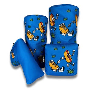 Puede incluir: Conjunto de cuatro cubrecabezas de golf azules con un diseño de dibujos animados de un perrito caliente y una lata de refresco. El perrito caliente y el refresco llevan gafas de sol y sonríen.