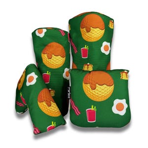 May include: Set of four green golf headcovers with a breakfast theme. The headcovers feature a waffle, bacon, eggs, and a bloody mary.