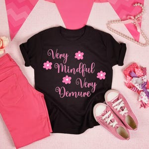 May include: Black t-shirt with the text "Very Mindful Very Demure" in pink lettering with pink flower accents.