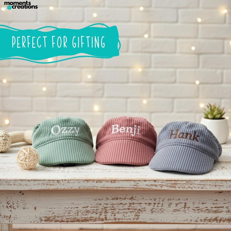 May include: Three corduroy caps in green, pink, and blue, each embroidered with a name: "Ozzy", "Benji", and "Hank". The caps are displayed on a white wooden surface. The text "PERFECT FOR GIFTING" is above the caps.