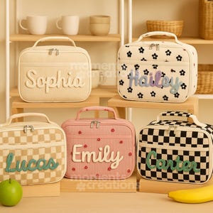 May include: Five personalized lunch bags in various colors and patterns. The bags feature names like "Sophia," "Hailey," "Lucas," "Emily," and "Carter." Designs include floral, checkered, and striped patterns, with matching handles and zippers.