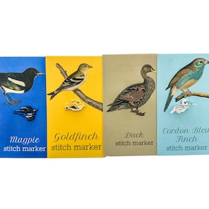 May include: Four colorful cards with illustrations of birds and the text "stitch marker" below each image. The birds are a magpie, a goldfinch, a duck, and a cordon bleu finch. Each card has a small metal pin of the bird on it.