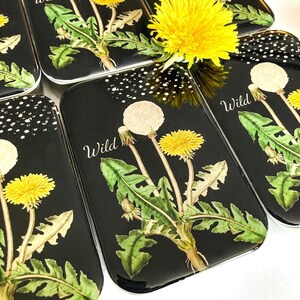 May include: Black rectangular trinket boxes with a dandelion design. The boxes feature a watercolor illustration of a dandelion with yellow flowers and white seed heads, with the word "Wild" in white script.