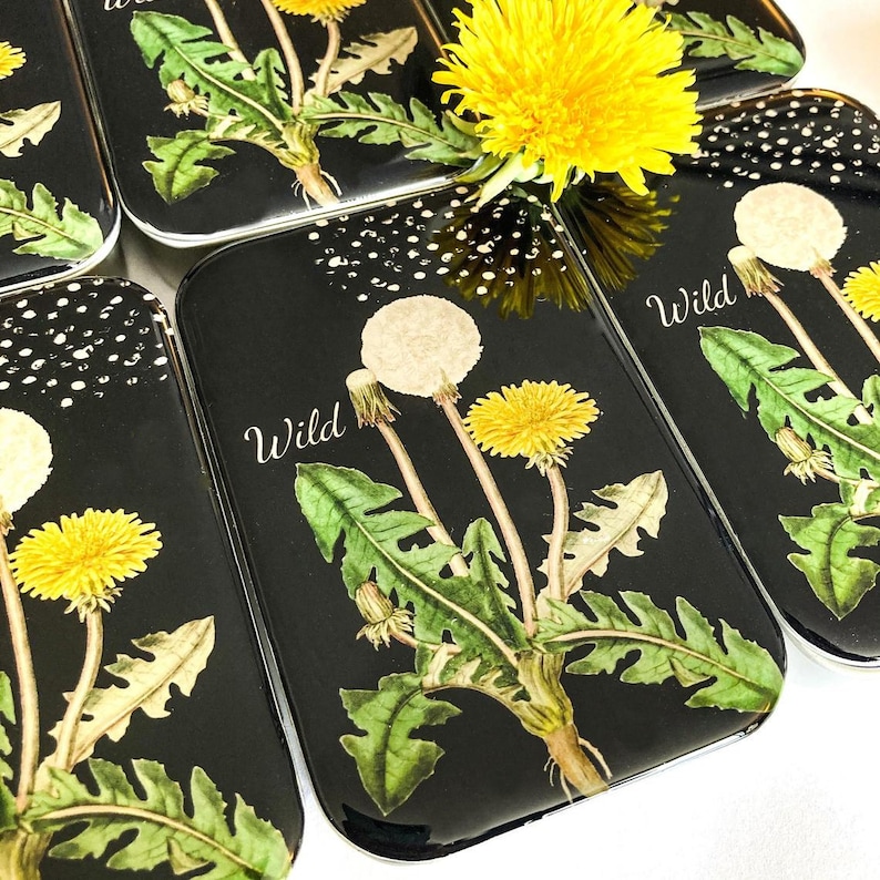 May include: Black rectangular trinket boxes with a dandelion design. The boxes feature a watercolor illustration of a dandelion with yellow flowers and white seed heads, with the word "Wild" in white script.