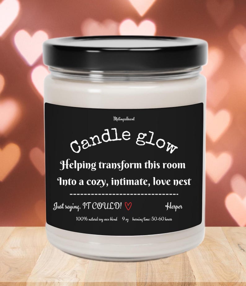 May include: A black and white candle jar with the text "Candle glow" and "Helping transform this room into a cozy, intimate, love nest. Just saying, IT COULD!" with a small heart symbol. The candle is 9 oz and has a burn time of 50-60 hours.