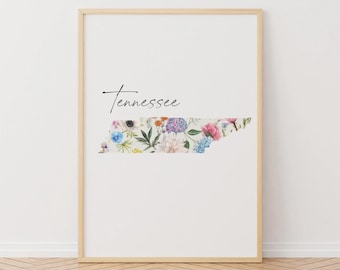 Könnte beinhalten: Ein druckbarer Kunstdruck mit einem floralen Design des Bundesstaates Tennessee. Der Druck ist weiß mit einem hellen Holzrahmen und das Wort "Tennessee" ist oben in schwarzer Kursivschrift geschrieben.