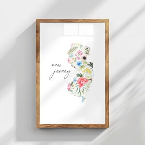 May include: A framed print of the state of New Jersey, outlined in floral designs. The print is on white paper with the words "new jersey" written in black cursive script.