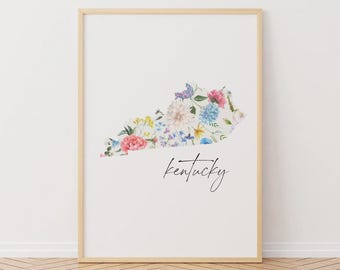 Könnte beinhalten: Ein floraler Druck des Bundesstaates Kentucky mit dem Wort "Kentucky" in Kursivschrift unterhalb der Umrandung. Der Druck ist auf weißem Hintergrund und in einem hellen Holzrahmen gerahmt.