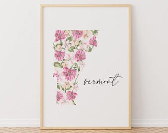 Könnte beinhalten: Ein gerahmter Druck mit dem Bundesstaat Vermont, gefüllt mit einem floralen Muster in Rosa, Weiß und Grün. Das Wort "vermont" ist in einer zarten Schrift darunter geschrieben. Der Rahmen hat eine helle Holzfarbe.