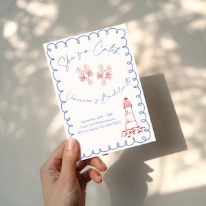 Peut inclure: Une invitation blanche avec une bordure ondulée bleue et du texte. L'invitation indique "She's a Catch, Veronica's Bachelorette" avec des illustrations de homard et de phare rouges. La date et le lieu sont également inclus.