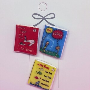 May include: Three miniature book-shaped pins featuring classic Dr. Seuss stories: "Green Eggs and Ham", "The Lorax", and "One Fish Two Fish Red Fish Blue Fish".