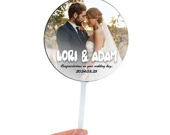 May include: A round, white, wedding cake topper with a photo of a couple and the text "LORI & ADAM Congratulations on your wedding day... 2024.03.25"