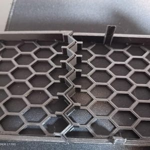 以下が含まれることがあります： 黒色のプラスチック製のハニカム形状のグリルをクローズアップ。グリルは、耐久性のある素材で作られており、洗練されたモダンなデザインです。