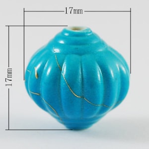 May include: A turquoise blue ceramic bead with gold crackle glaze. The bead is 1.69 inches in diameter.