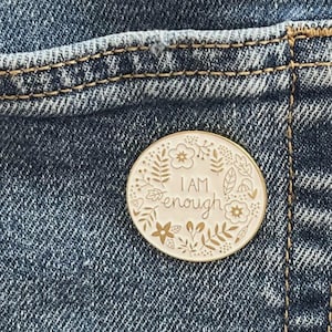 Könnte beinhalten: Ein weißer Holzstift mit goldenem Blumendesign und dem Text "I AM enough" in goldenen Buchstaben.