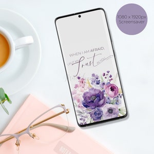 May include: A phone screen with a white background and purple flowers. The text on the screen reads "When I am afraid, I put my trust in you".