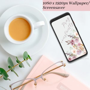 May include: A smartphone mockup with a floral design and the text "Pray constantly" on a white background. The phone is on a pink notebook with a pair of glasses and a cup of coffee on a white surface.