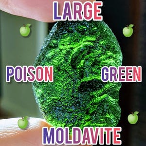 May include: A large, vibrant green Moldavite gemstone. The image features the words "LARGE", "POISON", "GREEN", and "MOLDAVITE" in colorful text. The gemstone is held between fingers.