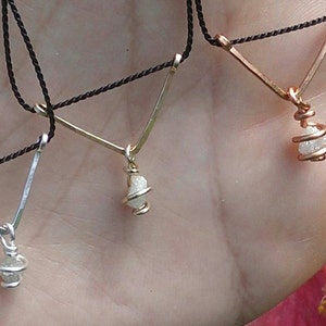 May include: Three necklaces with raw diamond pendants wrapped in wire. The necklaces are on a black cord and have a V-shaped design.