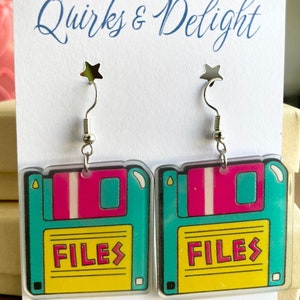 Peut inclure: Une paire de boucles d'oreilles en forme de disquette, de couleur turquoise et jaune, avec le mot "FILES" imprimé dessus. Les boucles d'oreilles sont faites à la main avec amour en Géorgie.