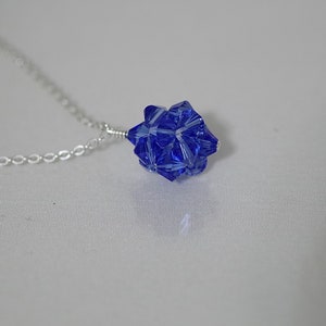 Puede incluir: Un collar de cadena de plata con un colgante de cristal azul en forma de estrella.