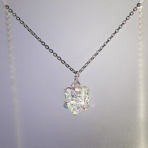 May include: A silver chain necklace with a crystal pendant. The pendant is made of many small, faceted crystals that are arranged in a cluster. The crystals are clear and sparkle in the light.